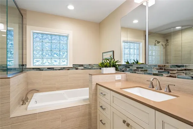 a bathroom with a granite countertop tub sink and mirror