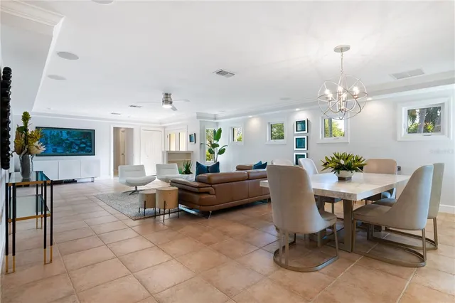 a living room with couches a table and chairs with potted plants