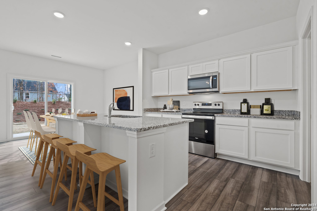 124 Dionicio Loop Seguin, TX 78155 - Photo 2 of 17 a kitchen with stainless steel appliances granite countertop white cabinets a sink a stove a dining table and chairs