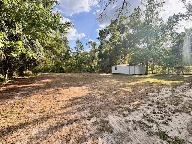 a view of a small house with backyard and wooden fence