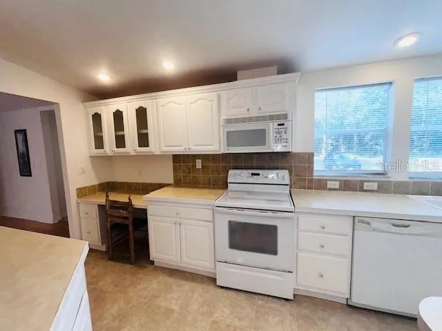 a kitchen with white cabinets sink and stove