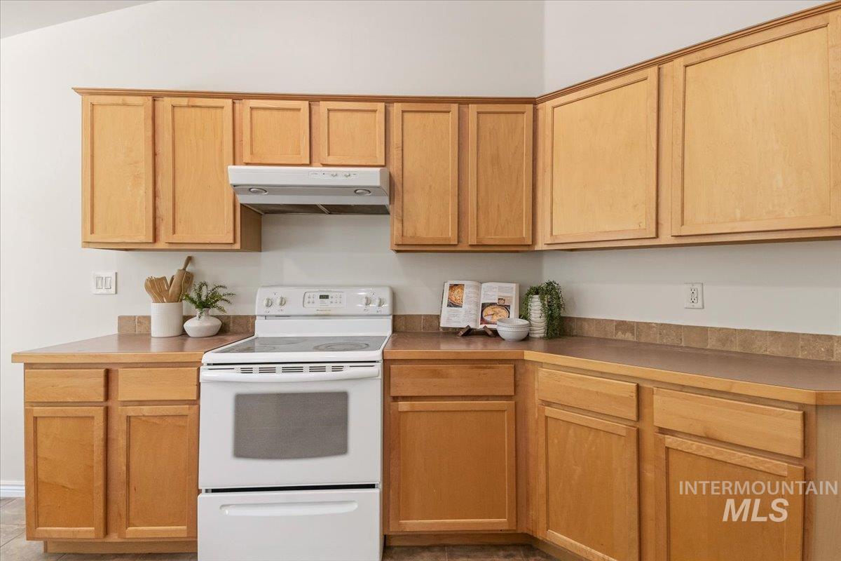 2032 Talus Loop Twin Falls, ID 83301 - Photo 16 of 43 Corner kitchen with light wood-finish cabinetry, a white electric range, and a matching range hood