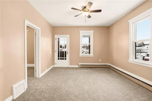 an empty room with a ceiling fan and carpet