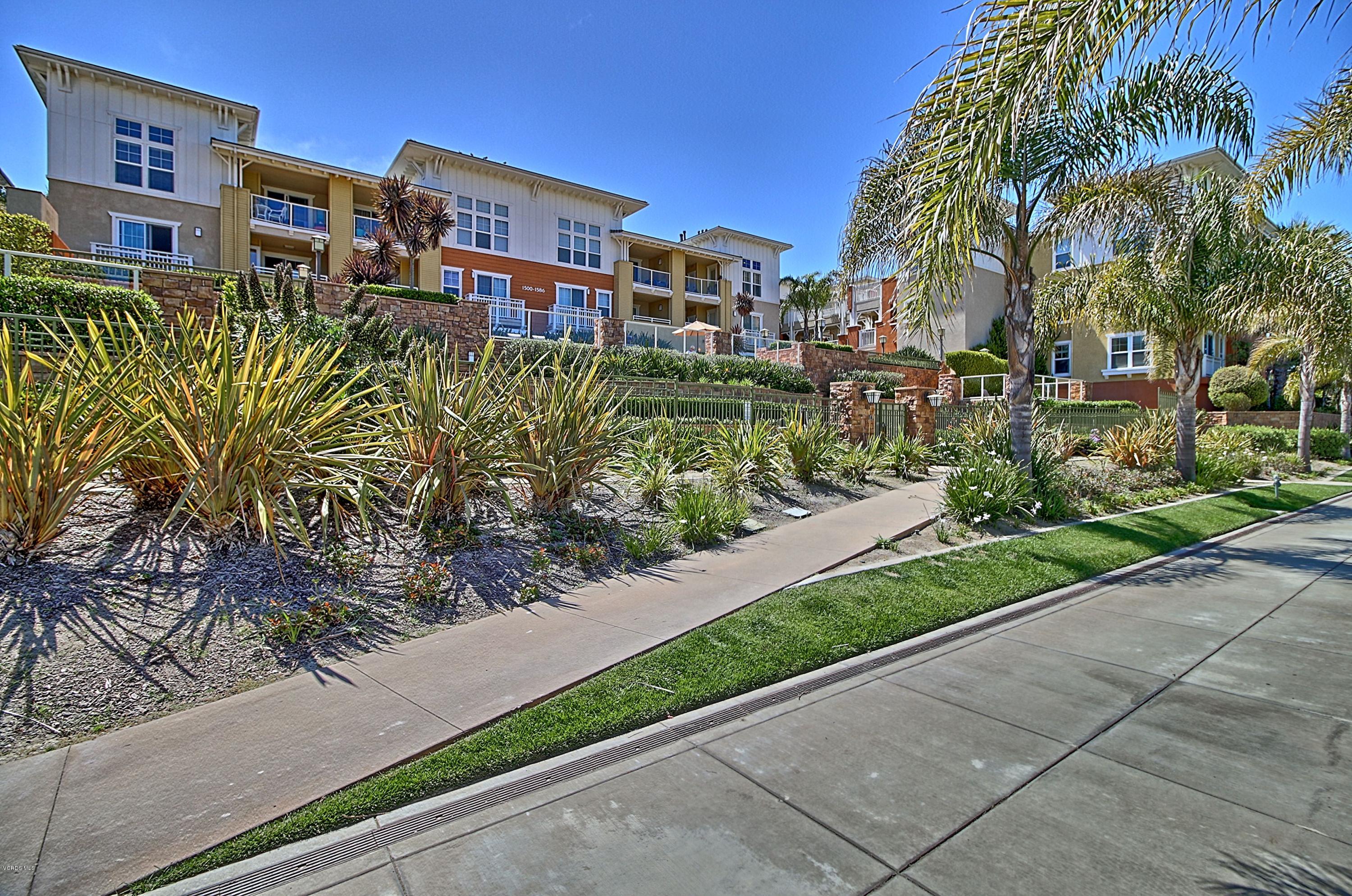 1568 Seabridge Lane Oxnard, CA 93035 - Photo 4 of 33 a front view of a multi story residential apartment building with yard and bench