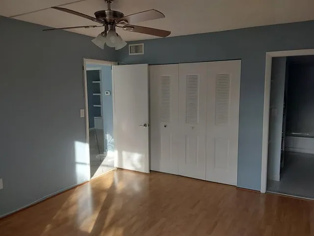 a view of an empty room with window and wooden floor