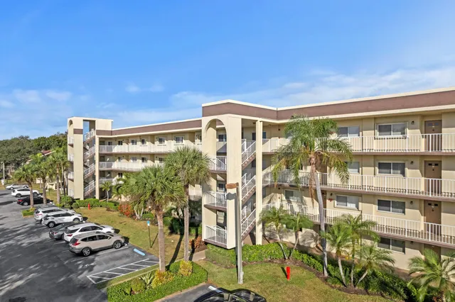a front view of a building with glass windows and plants
