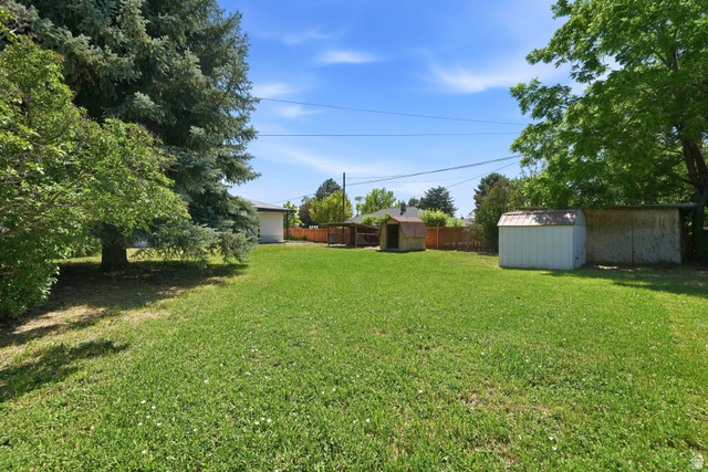 546 West 200 South Payson, UT 84651 - Photo 32 of 45 Expansive backyard featuring a lush lawn, mature trees providing shade, and two storage sheds