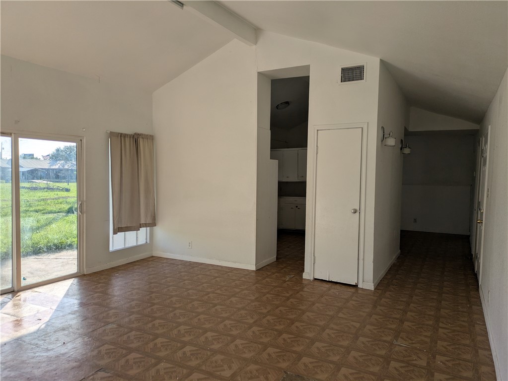 124 Redwood Drive Mathis, TX 78368 - Photo 4 of 10 an empty room with windows and entrance to other room