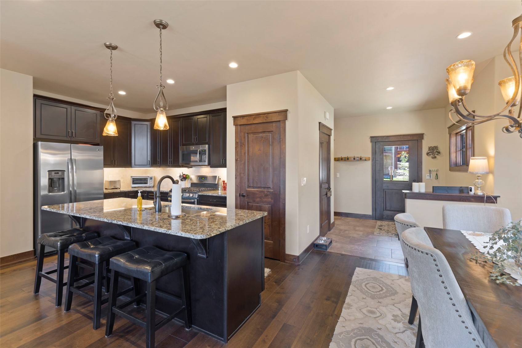 799 Independence Road, Unit 799 Keystone, CO 80435 - Photo 13 of 44 Kitchen with appliances with stainless steel finishes, dark brown cabinets, light stone counters, a kitchen bar, and dark wood-style flooring