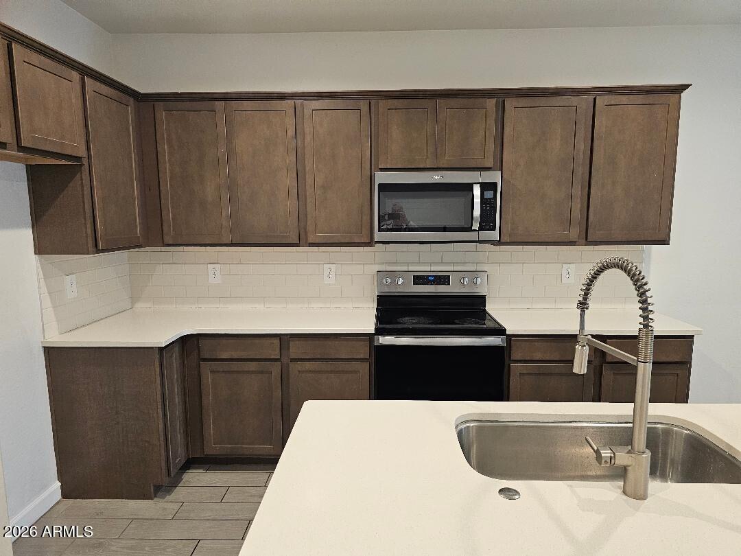 24151 West Ripple Road Buckeye, AZ 85326 - Photo 4 of 13 a kitchen with granite countertop a sink and a stove top oven with wooden cabinets