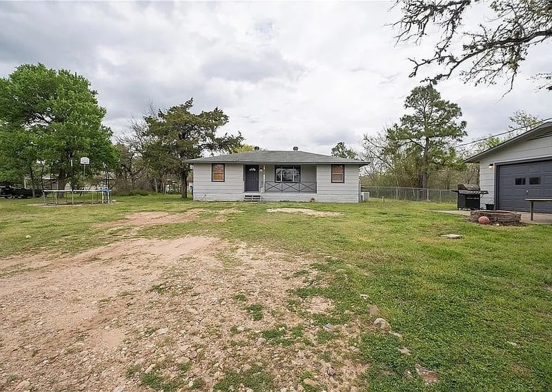 a view of a house with a big yard and large trees
