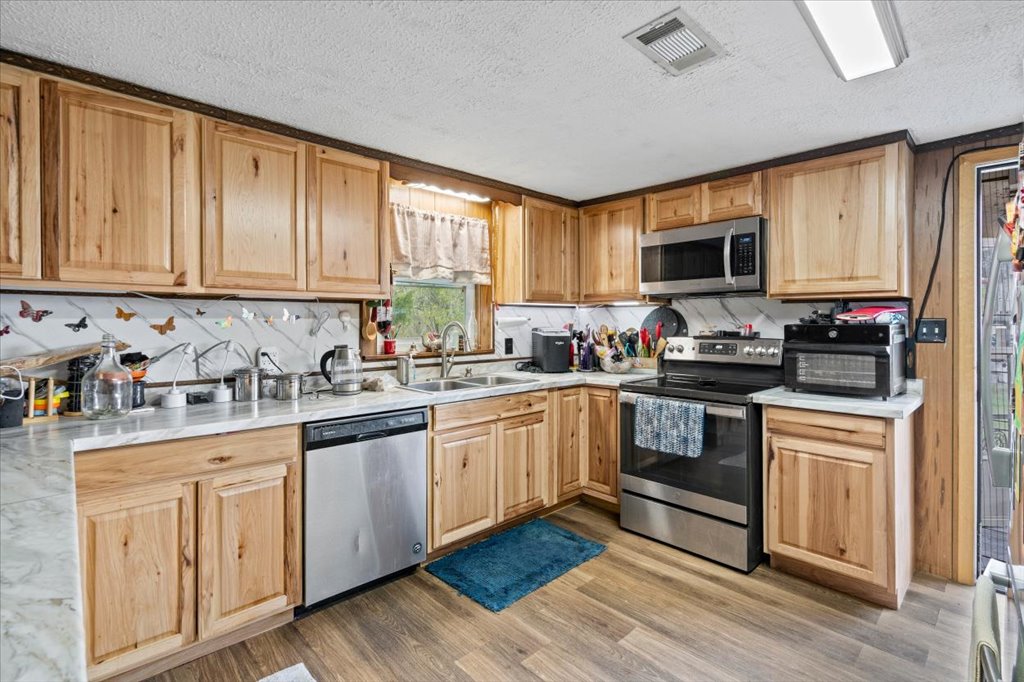 250 Rick Road La Grange, TX 78945 - Photo 21 of 27 a kitchen with kitchen island granite countertop a stove top oven a sink dishwasher and white cabinets with wooden floor