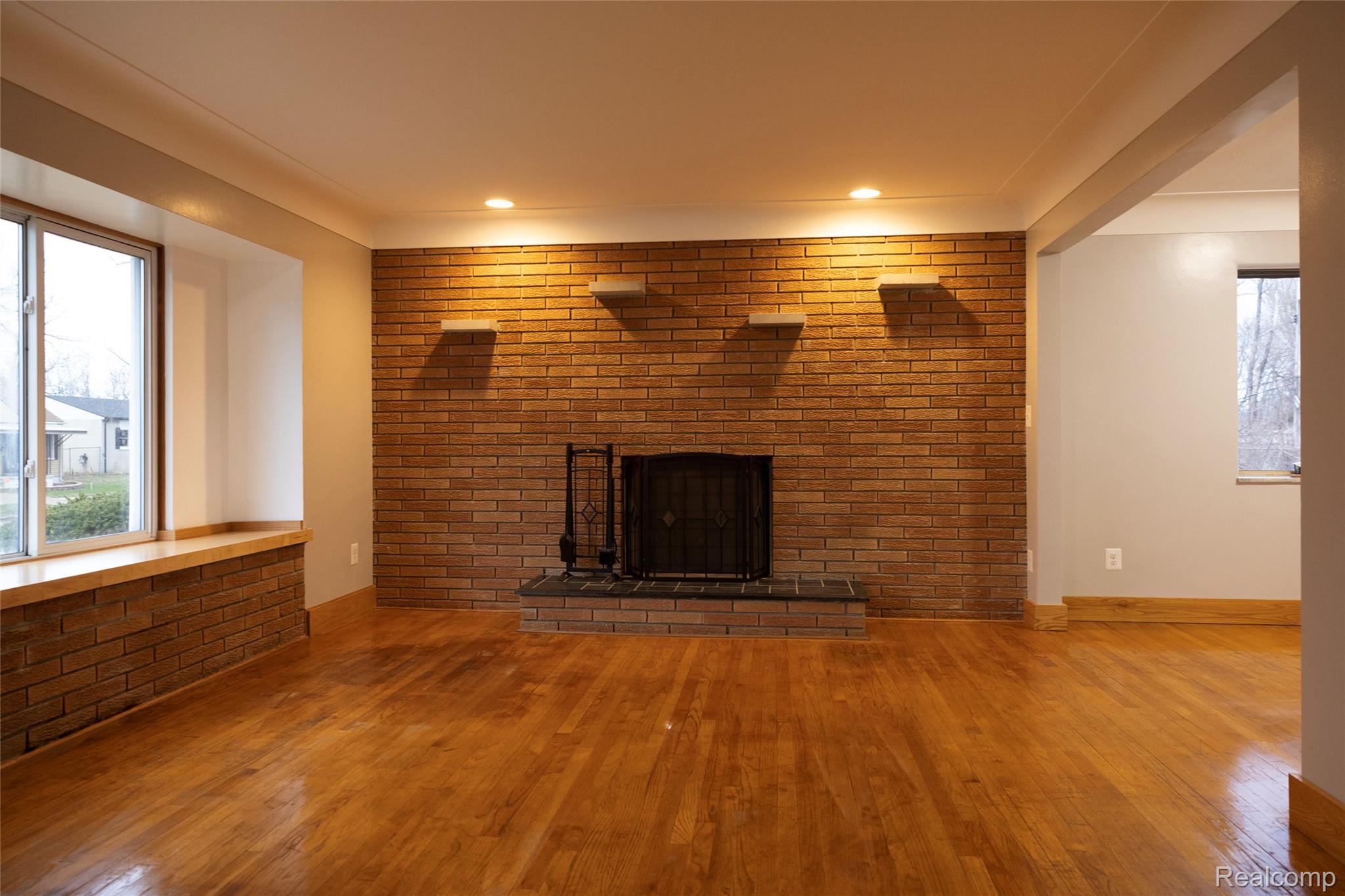 4191 Allen Avenue Inkster, MI 48141 - Photo 5 of 13 Unfurnished living room with hardwood / wood-style floors, brick wall, and a fireplace