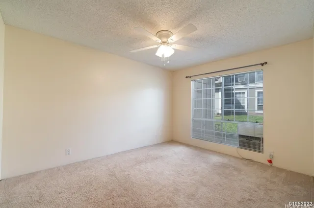 an empty room with windows and ceiling fan