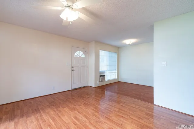 a view of an empty room with window and wooden floor