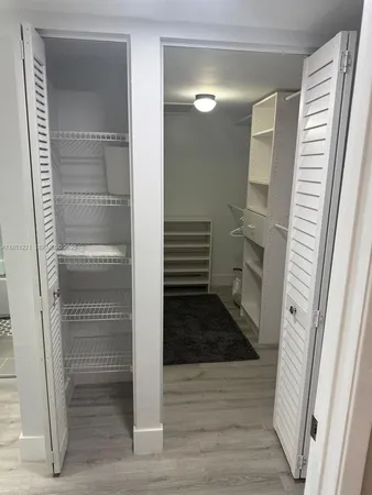 a bathroom with a walk in closet and wooden floor