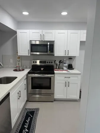 a kitchen with white cabinets stainless steel appliances and sink