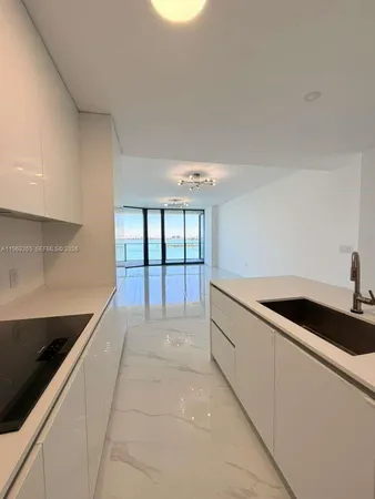 a large white kitchen with a sink and cabinets