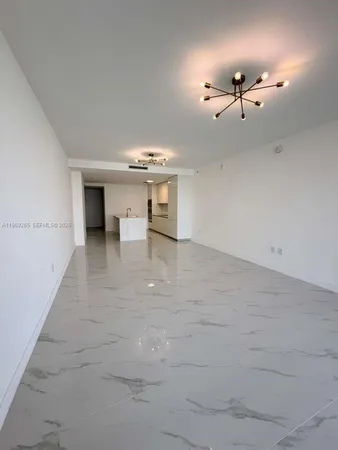 a view of an empty room with a chandelier fan