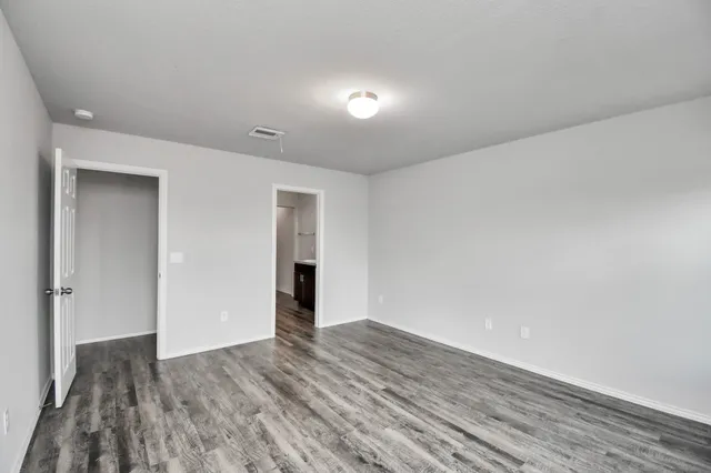 a view of an empty room with wooden floor and closet