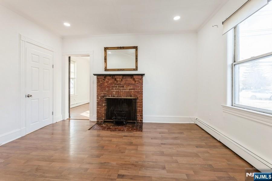 21 Central Avenue Tenafly, NJ 07670 - Photo 4 of 22 an empty room with wooden floor a fireplace and a window