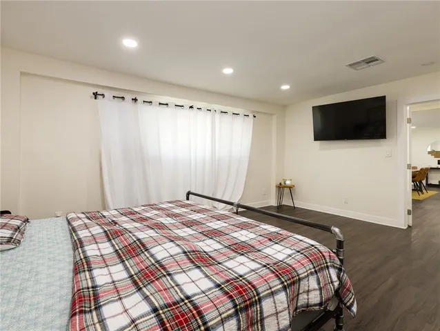 a bedroom with a bed a flat screen tv and a window