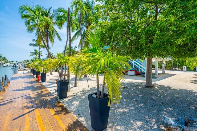 a open kitchen with stainless steel appliances granite countertop a stove top oven a sink dishwasher a dining table and chairs with wooden floor