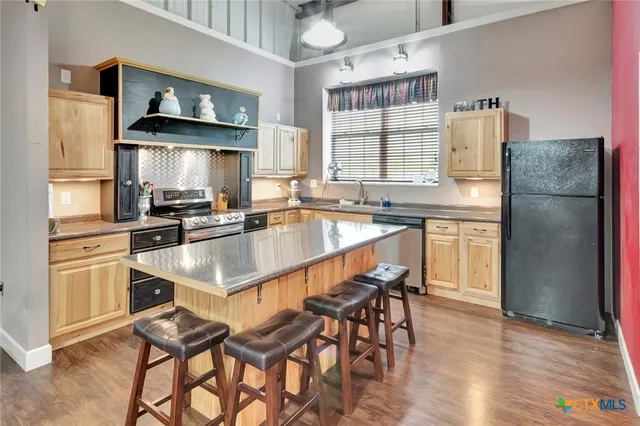 a kitchen with granite countertop stainless steel appliances a sink and a refrigerator