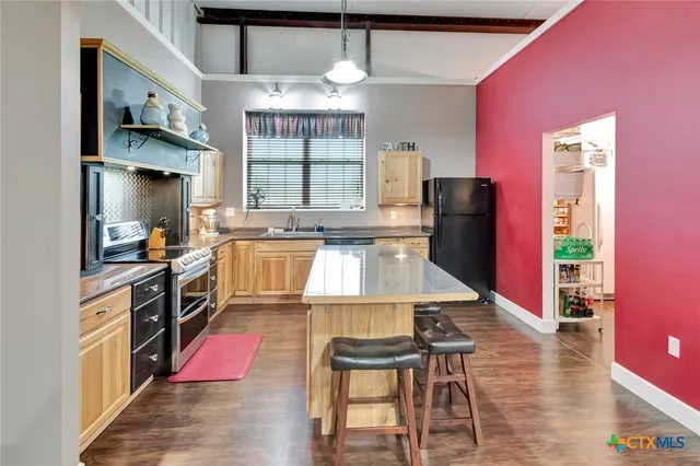 a kitchen with stainless steel appliances kitchen island granite countertop a refrigerator a stove top oven a sink and dishwasher a oven with wooden floor