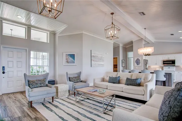 a living room with furniture kitchen view and a chandelier