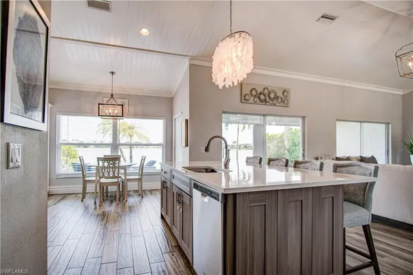 a kitchen with stainless steel appliances granite countertop a refrigerator a sink dishwasher a stove and white countertops with wooden floor
