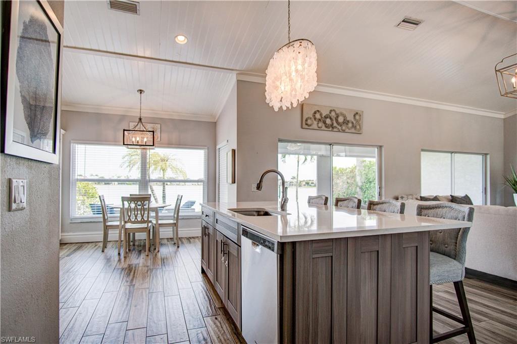 7271 Mill Pond Circle Naples, FL 34109 - Photo 10 of 45 a kitchen with stainless steel appliances granite countertop a stove a kitchen island a dining table and chairs with wooden floor