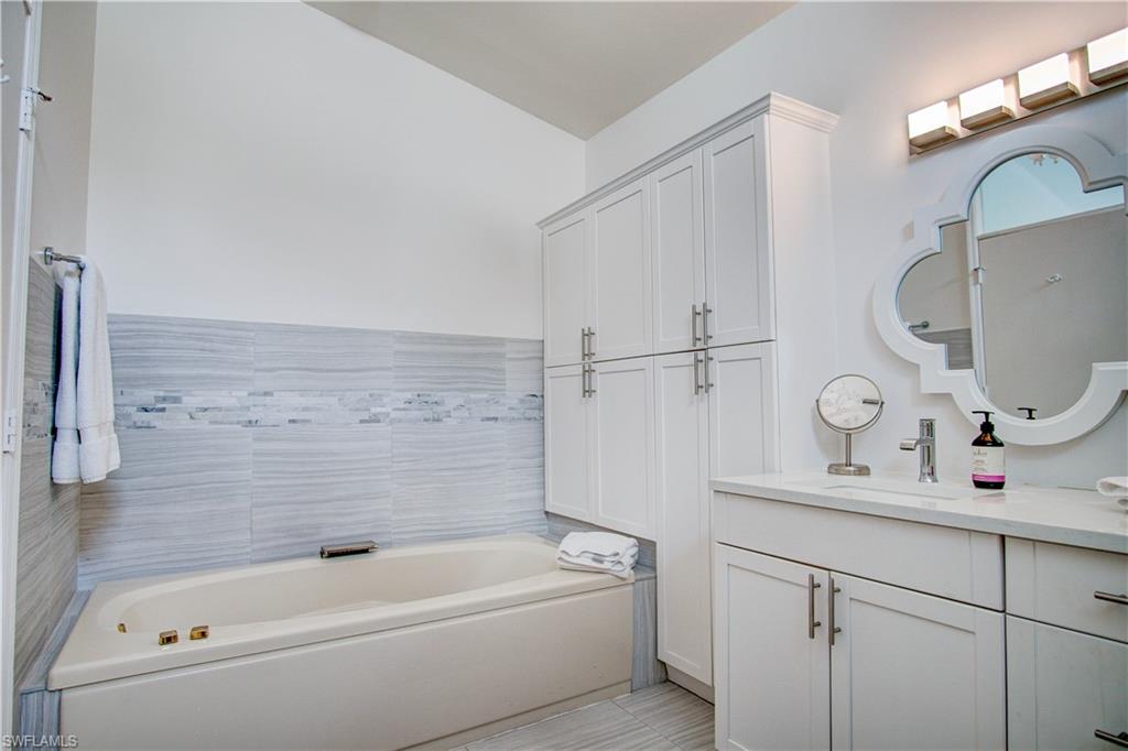 7271 Mill Pond Circle Naples, FL 34109 - Photo 14 of 45 a bathroom with a tub a sink and a mirror