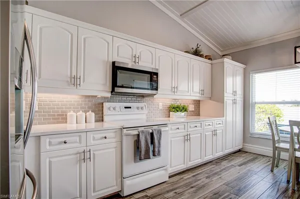 a kitchen with stainless steel appliances granite countertop a stove a kitchen island a dining table and chairs with wooden floor