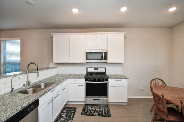 a kitchen with granite countertop a stove a sink and a microwave