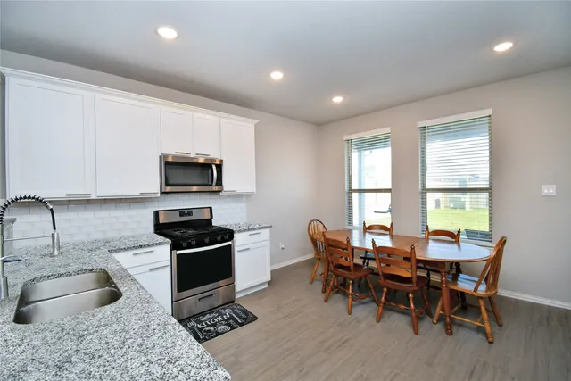 a kitchen with stainless steel appliances granite countertop a stove a sink a microwave a dining table and chairs