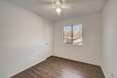 an empty room with wooden floor chandelier fan and windows