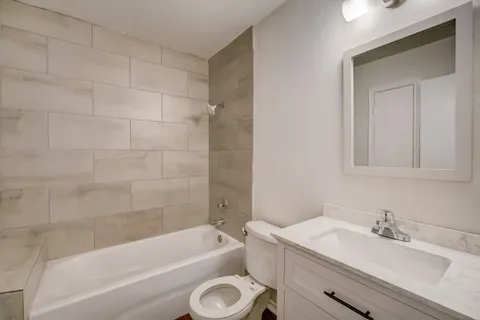 a bathroom with a granite countertop bathtub shower sink vanity and toilet