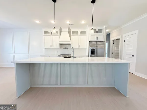 a kitchen with kitchen island white cabinets and refrigerator