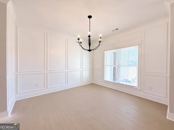 an empty room with chandelier fan and windows