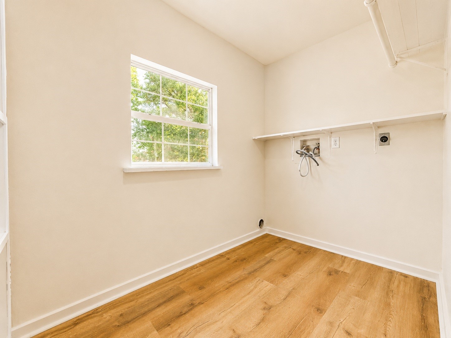 316 Riley Road Clute, TX 77531 - Photo 19 of 21 Bright laundry room with wood-style flooring, a large window for natural light, and convenient shelving above washer/dryer hookups.