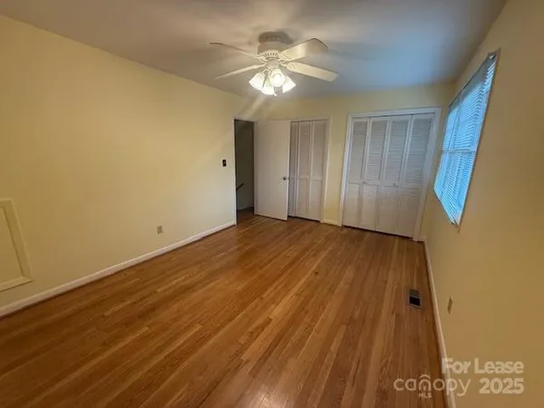 a view of a room with wooden floor and a ceiling fan
