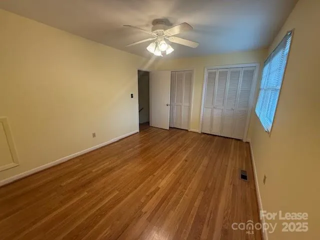 a view of a room with wooden floor and a ceiling fan
