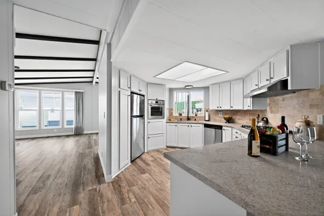 a kitchen with stainless steel appliances granite countertop a refrigerator oven stove a sink and dishwasher with wooden floor