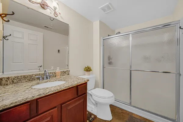a bathroom with a granite countertop sink toilet and shower