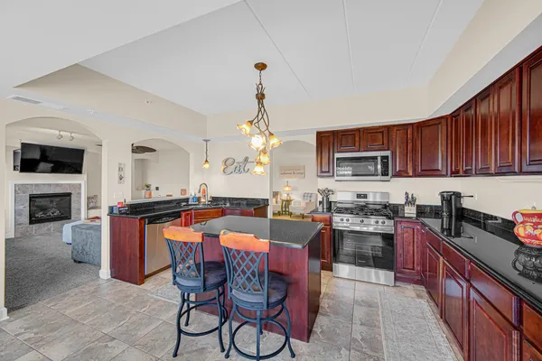 a kitchen with stainless steel appliances granite countertop a stove top oven a sink dishwasher a dining table and chairs with wooden floor