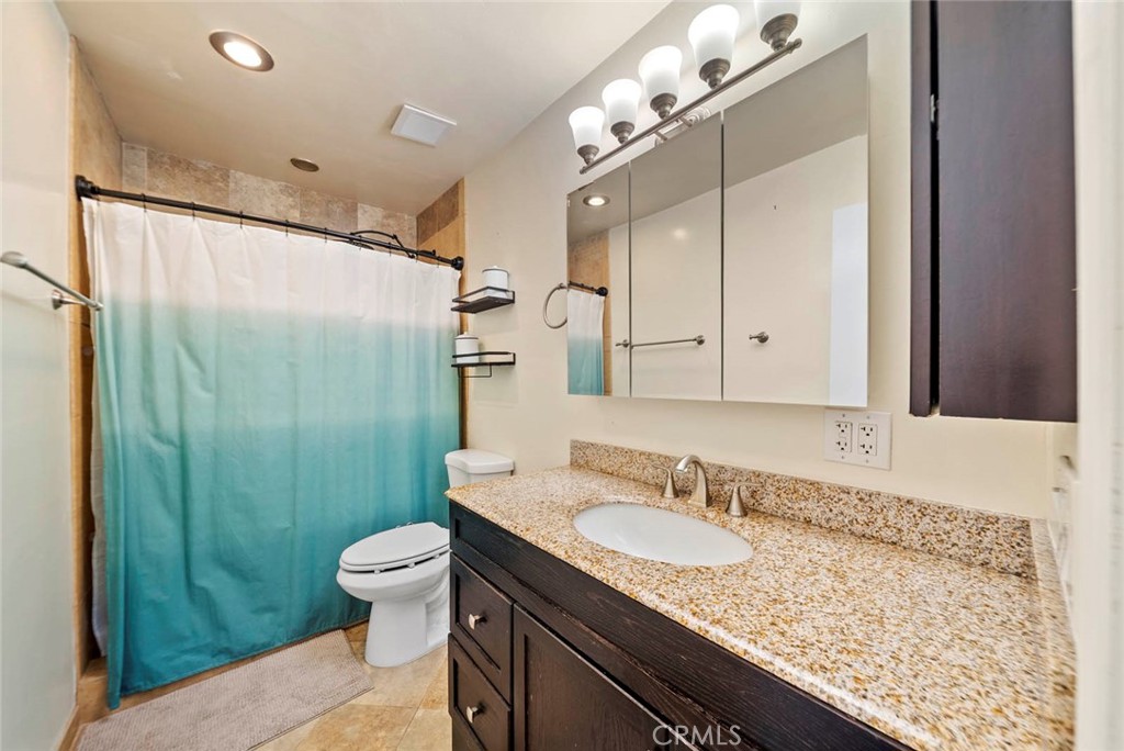 10634 Sanfred Court Santee, CA 92071 - Photo 17 of 44 a bathroom with a granite countertop sink a toilet a mirror and shower