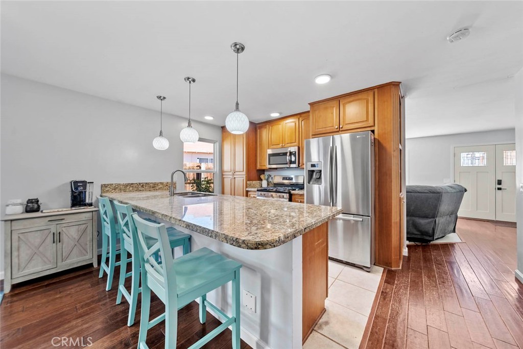 10634 Sanfred Court Santee, CA 92071 - Photo 7 of 44 a kitchen with stainless steel appliances granite countertop a kitchen island a stove a refrigerator a sink a dining table and chairs with wooden floor
