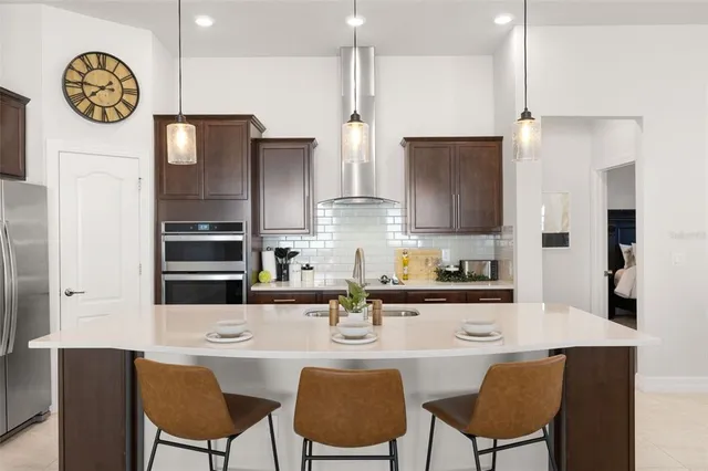 a kitchen with stainless steel appliances a refrigerator a stove a dining table and chairs