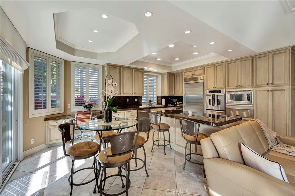 6096 Eaglecrest Drive Huntington Beach, CA 92648 - Photo 20 of 64 a kitchen with stainless steel appliances kitchen island granite countertop a refrigerator a stove a sink a dining table and chairs with wooden floor